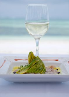 a white plate topped with food next to a glass of wine