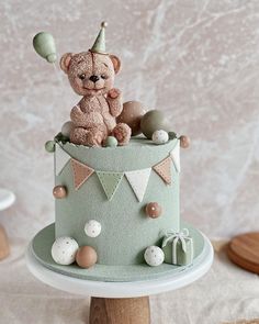 a teddy bear sitting on top of a green cake with bunting and eggs around it