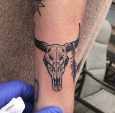 a person with a tattoo on their arm has a bull's skull and arrows