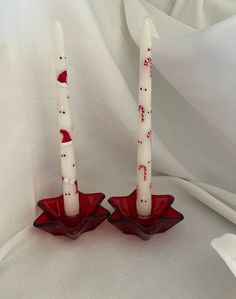 two candles sitting on top of a red bowl