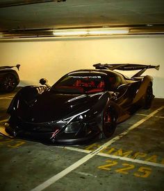 two black sports cars parked next to each other in a parking garage with yellow numbers on the floor