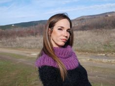 a woman with long hair wearing a purple and black knitted cowgirl neck sweater