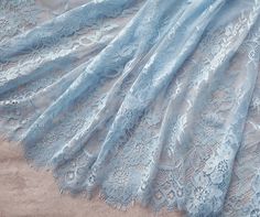 a blue lace fabric with flowers and leaves on it's edge, laying on the ground