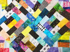 a colorful quilt made up of different colored squares and strips on the side of it