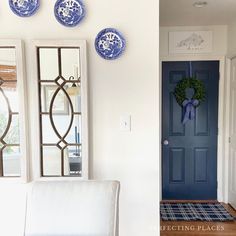 two blue and white plates hanging on the wall next to a chair in front of a door