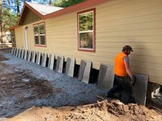 a man in an orange shirt and black pants is working on the side of a house