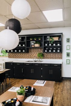 a kitchen with black cabinets and wooden tables in front of the counter top is filled with potted plants