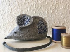 a gray mouse sitting on top of a table next to spools of thread