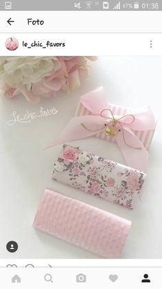 some pink and white items are laying on a table with flowers in the back ground