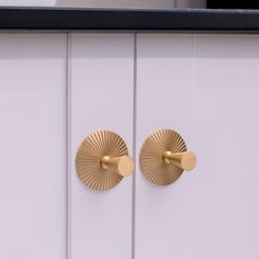 two gold handles on white cupboards with black trim