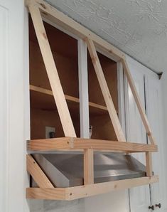 an unfinished kitchen cabinet is shown with the door open and shelves in place for cooking utensils