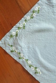 a table cloth with white flowers on it sitting on a wooden floor in front of a pair of scissors