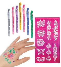 a person's hand with temporary tattoos on it and five pens in the background