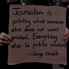 a person holding a sign that says journalism is printing what someone else does not want printed everything else is public relations