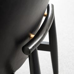 the back of a black chair with gold detail on it's armrests