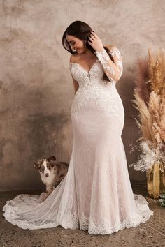 a woman in a wedding dress standing next to a dog