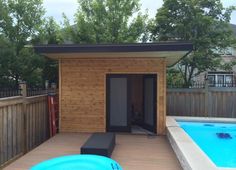 a small wooden shed with a pool in the back ground and an above ground hot tub