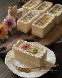 a piece of cake sitting on top of a white plate next to flowers and a fork