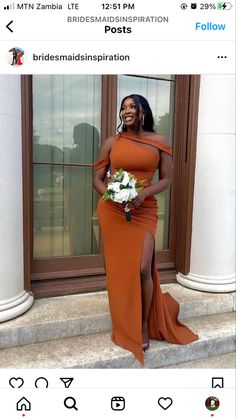 a woman in an orange dress standing on steps with her legs crossed and holding a bouquet