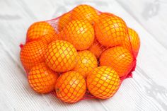 a mesh bag filled with oranges on top of a white surface