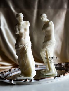 two white statues sitting on top of a plate