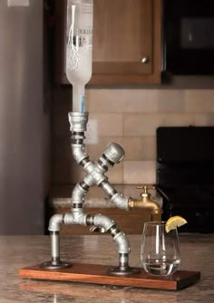 a wine glass holder made out of metal pipes on a wooden board with a shot glass next to it