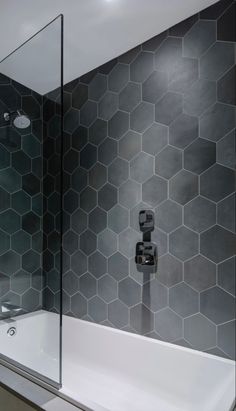 a modern bathroom with hexagonal tiles on the wall and bathtub in the corner