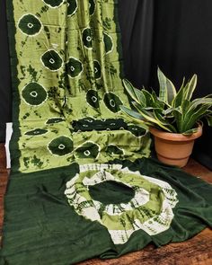 a potted plant sitting on top of a wooden table next to a green blanket