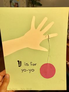 a hand holding up a piece of paper with the words u is for yo - yo on it