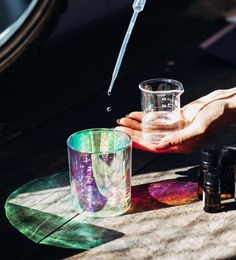 a person is holding a glass with water in it and some other items on the table