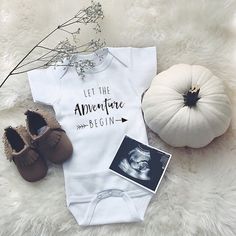 a baby's bodysuit, shoes and pumpkins on a white fur rug