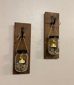 two mason jar wall sconces with lights in them hanging on a white wall