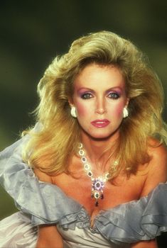 a woman with blonde hair and blue eyes posing for a photo in a white dress