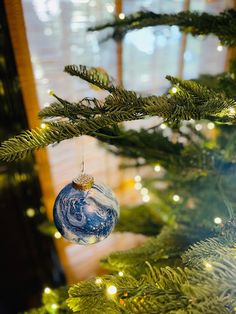 a blue and white ornament hanging from a christmas tree