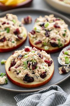 an apple filled with chicken salad and garnished with cranberries on a plate