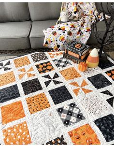 an orange and black quilt sitting on top of a couch next to a white pillow