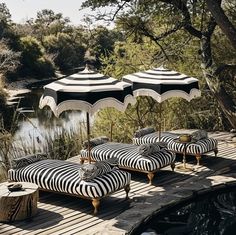 zebra print chaise lounges and umbrellas on a wooden deck overlooking a pond