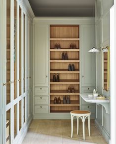 an empty room with wooden shelves and shoes on the floor, in front of a dressing table