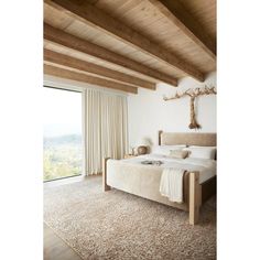 a bedroom with a large bed and wooden beams on the ceiling, along with an open window