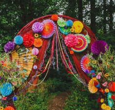 colorful paper fans and streamers decorate the entrance to a garden wedding ceremony in an outdoor setting