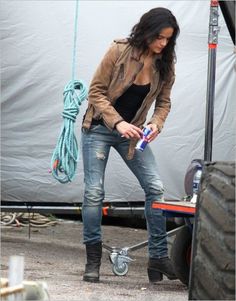 a woman standing next to a truck holding a water bottle in her right hand and looking down at the ground