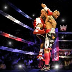 two men standing next to each other on top of a boxing ring in front of a crowd