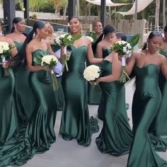 a group of women standing next to each other wearing green dresses and holding bouquets