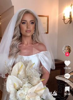 a woman in a wedding dress holding a bouquet with flowers on the table next to her