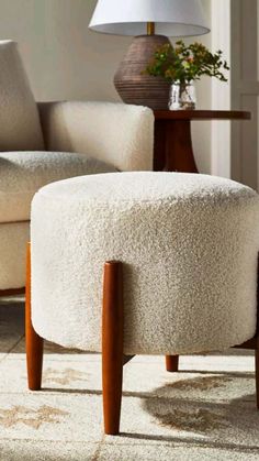 a white ottoman sitting on top of a rug next to a table with a lamp