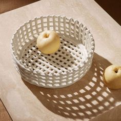 an apple is sitting in a white basket on a counter top next to two apples