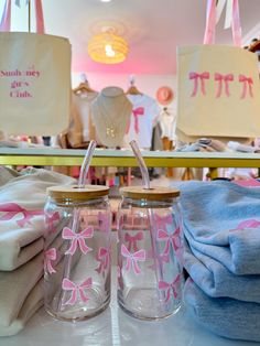 two glass jars with pink bows on them are sitting on a table next to folded towels