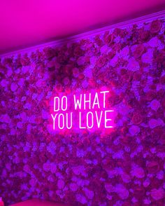 a pink wall with flowers and the words do what you love written in neon lights