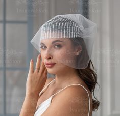 a woman with a veil on her head is looking at the camera while she holds her hand up to her face