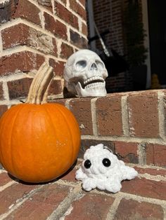 a pumpkin sitting on the ground next to a fake skull and a small white ghost